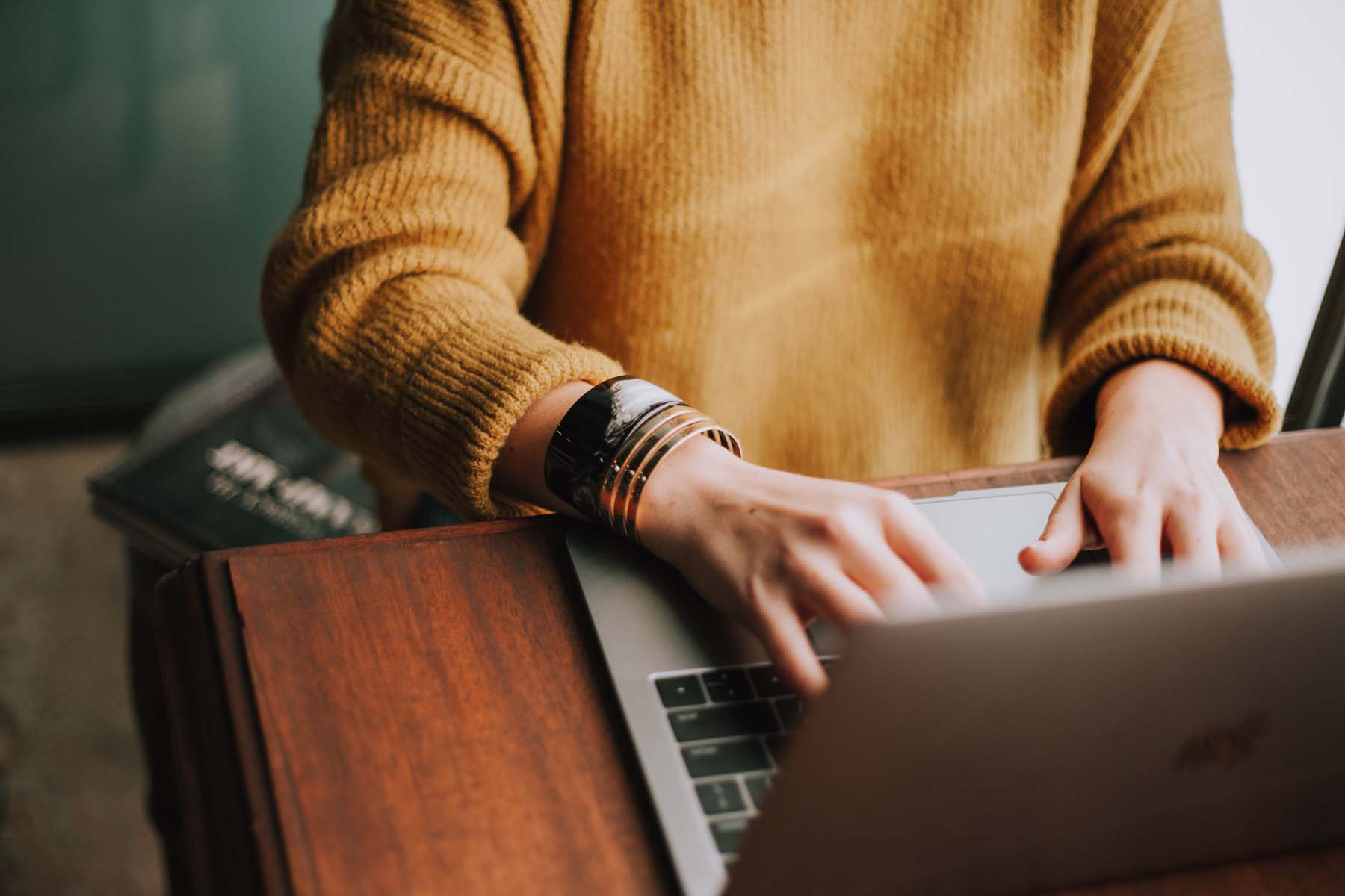 A woman typing on a laptop during an online therapy session